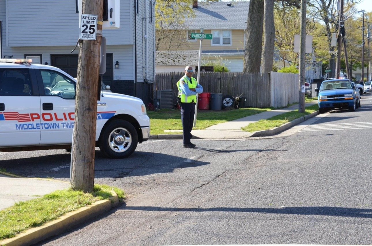Middletown Township Auxiliary officer directing traffic beside a Middletown Township Police vehicle